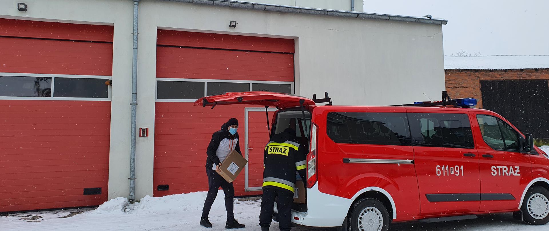Strażacy przekazujący środki do dezynfekcji oraz maseczki dla OSP biorące udział w akcji Narodowego Programu Szczepień Przeciw Covid -19