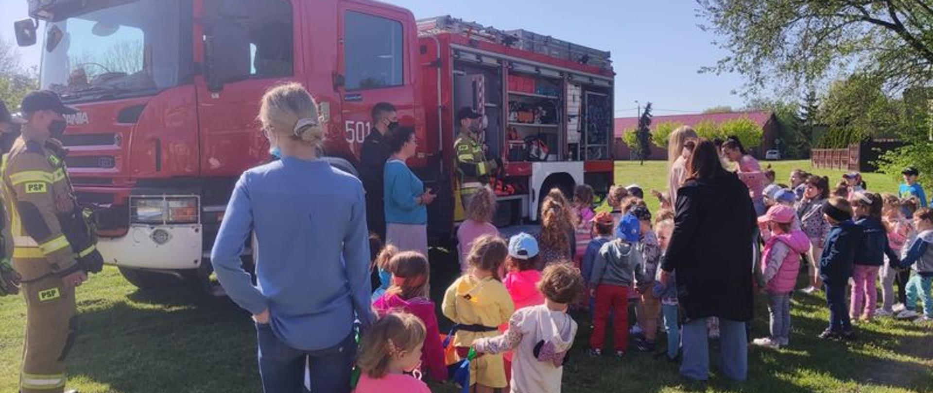 Zdjęcie przedstawia strażaków prezentujących dzieciom samochody gaśnicze JRG PSP Radziejów