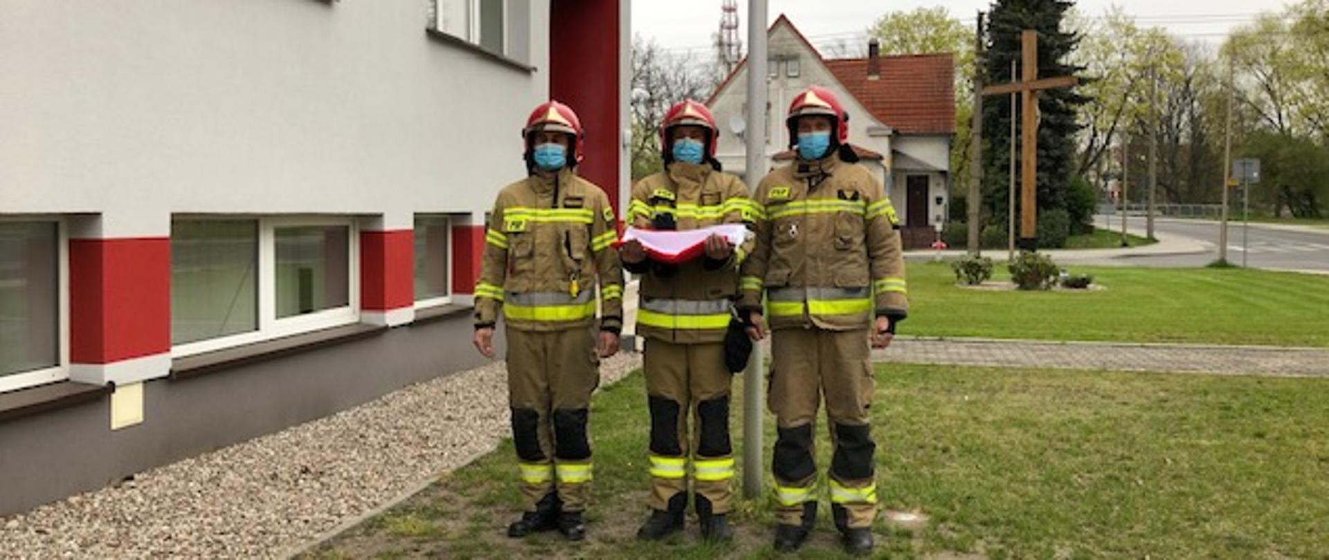 Strażacy JRG trzymający flagę państwową