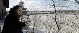 Minister Katarzyna Pełczyńska-Nałęcz stoi na balkonie i patrzy na drzewa.