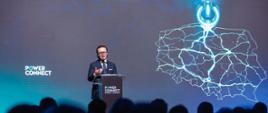 Minister Wojciech Balczun stoi za mównicą. W tle ekran z mapą Polski i napisem Power Connect. 