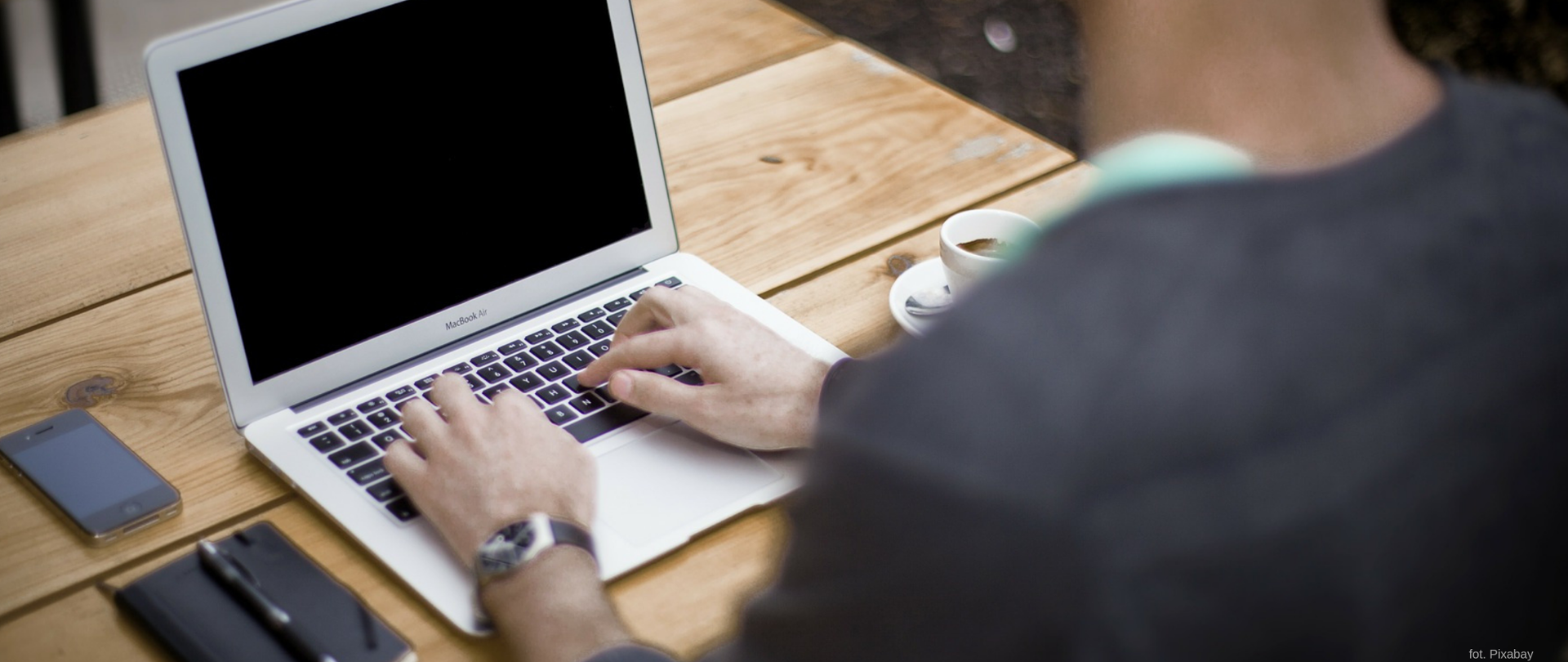 Mężczyzna siedzący przed laptopem.