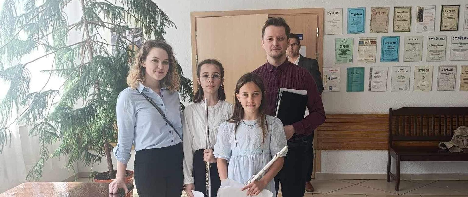 Zdjęcie nauczycielki oraz akompaniatora wraz z uczennicami w holu szkoły