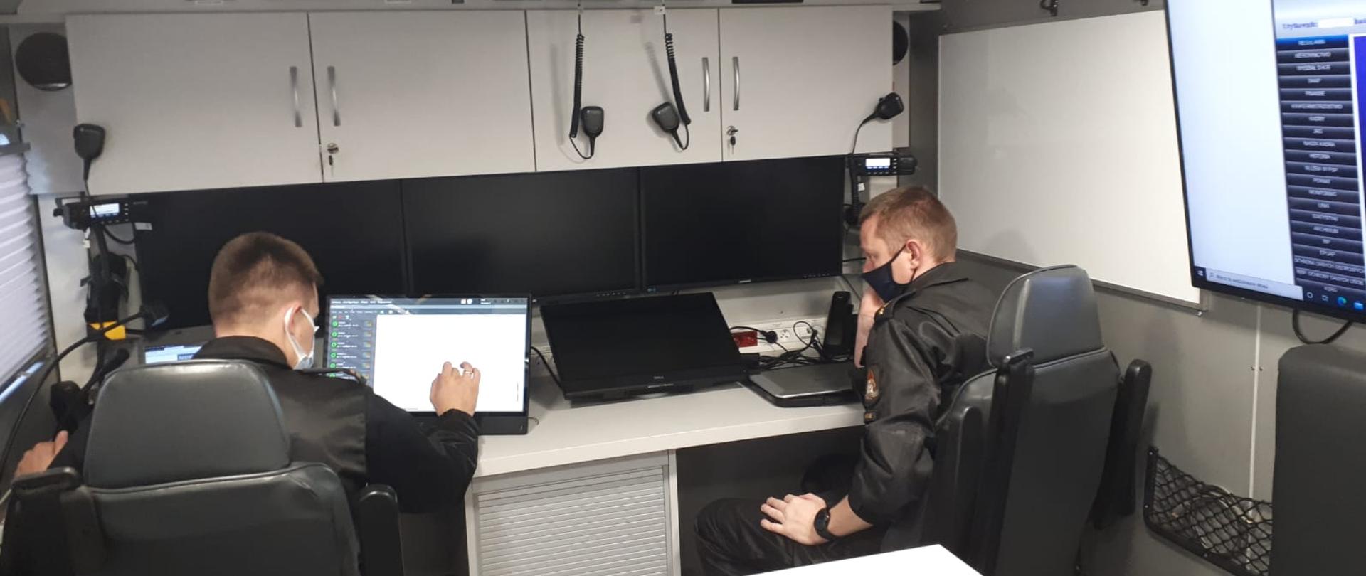 Strażacy po próbnej ewakuacji ze stanowiska kierowania pracują w samochodzie dowodzenia i łączności