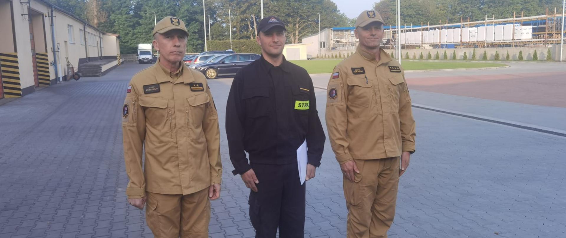 Zdjęcie przedstawia trzech strażaków podczas awansu na młodszego ratownika-kierowcę