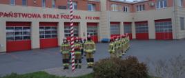 Funkcjonariusze Komendy Powiatowej Państwowej Straży Pożarnej w Pruszczu Gdańskim na placu przed budynkiem Komendy są w trakcie uroczystego podniesienia flagi narodowej na maszt.