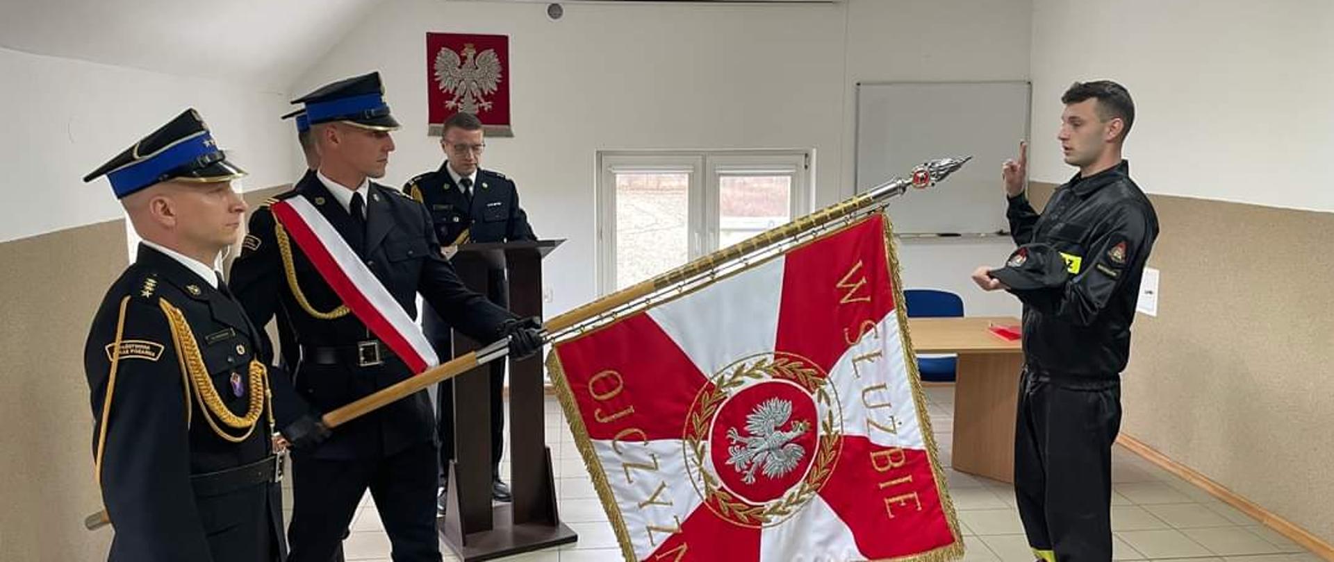 Zdjęcie przedstawia strażaków PSP ze sztandarem KP PSP Radziejów podczas uroczystego ślubowania nowo przyjętego strażaka.