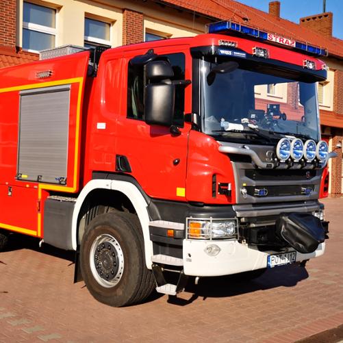Na zdjęciu ciężki samochód gaśniczy Scania na placu manewrowym przed garażami Jednostki Ratowniczo-Gaśniczej