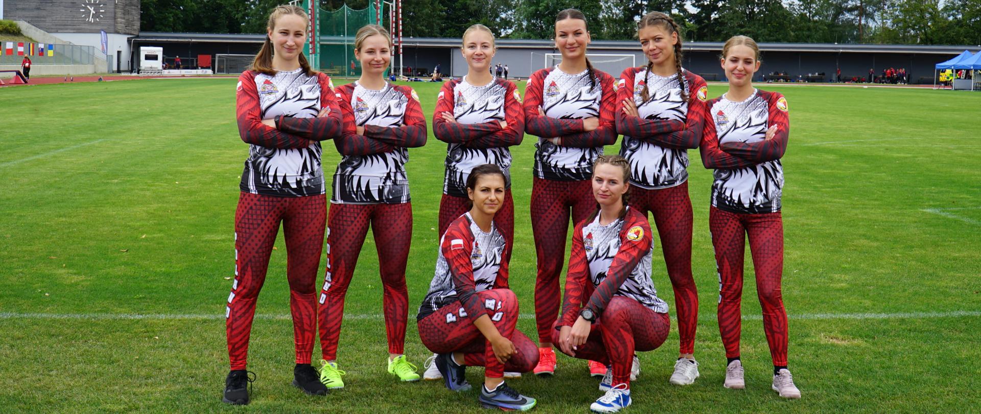 Pamiątkowe zdjęcie zawodniczek drużyny Centralnej Szkoły PSP (8 kobiet) w sporcie pożarniczym na murawie stadionu