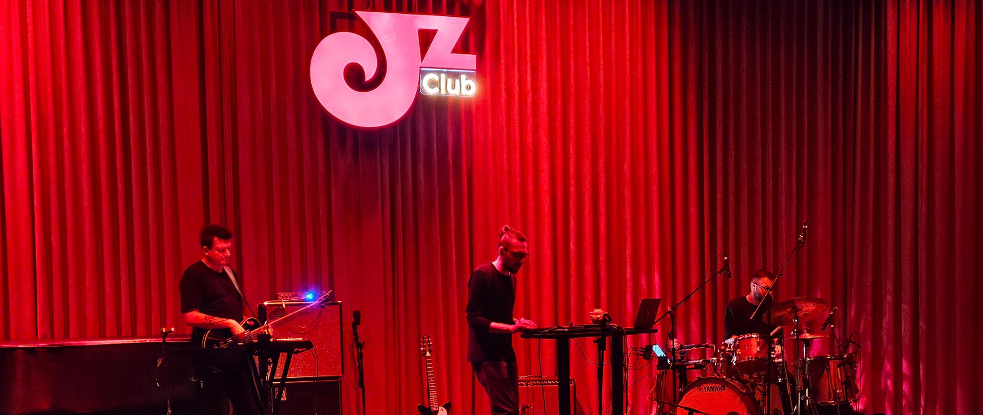 band jazzowy gra na scenie klubu oświetlonego ciemnym, czerwonym światłem