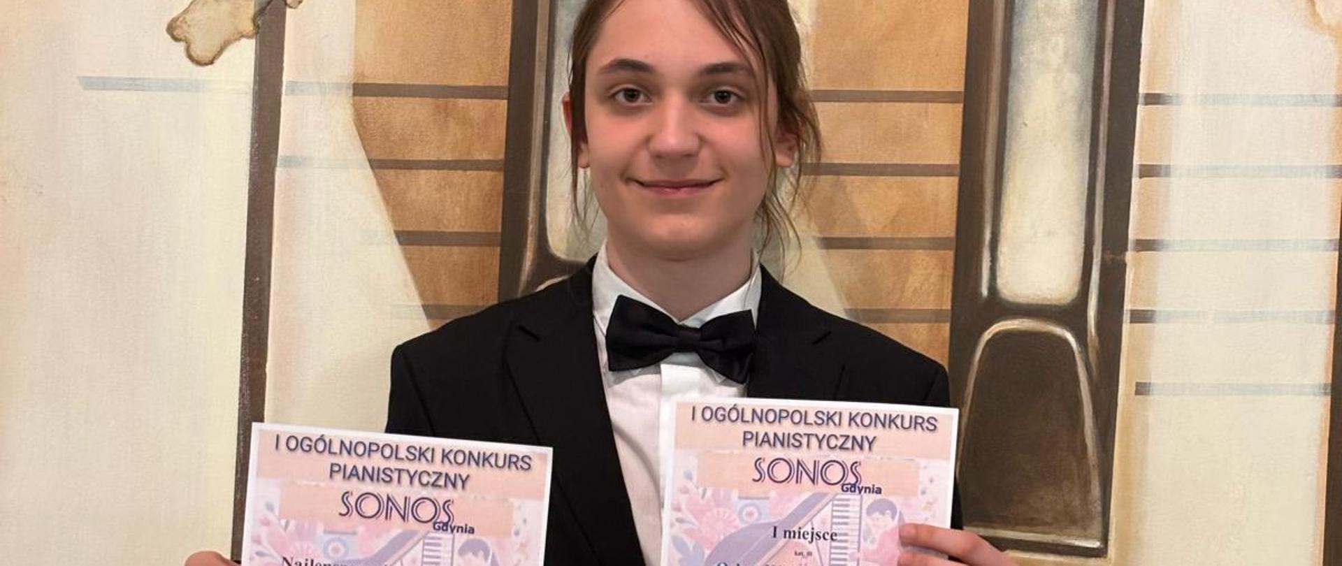 uczeń trzymający dyplomy