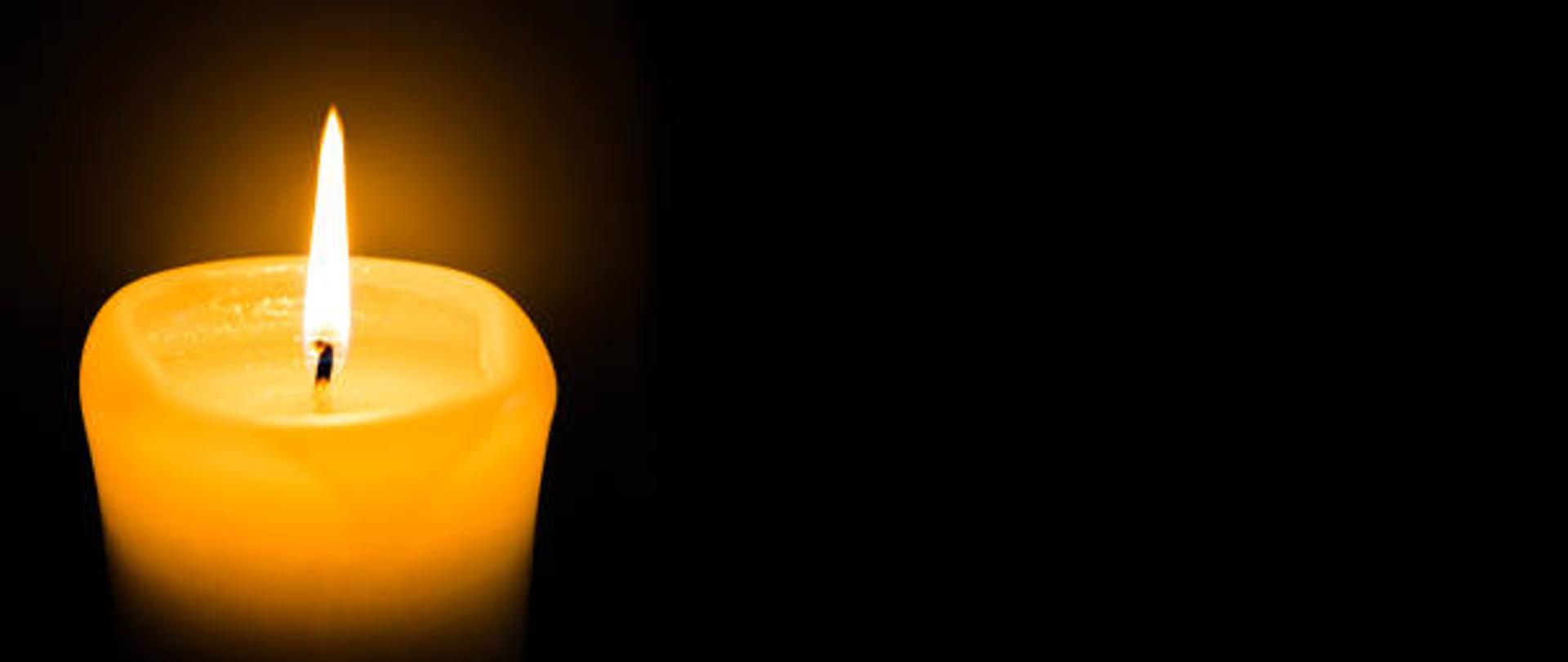 Płonąca świeca na czarnym tle