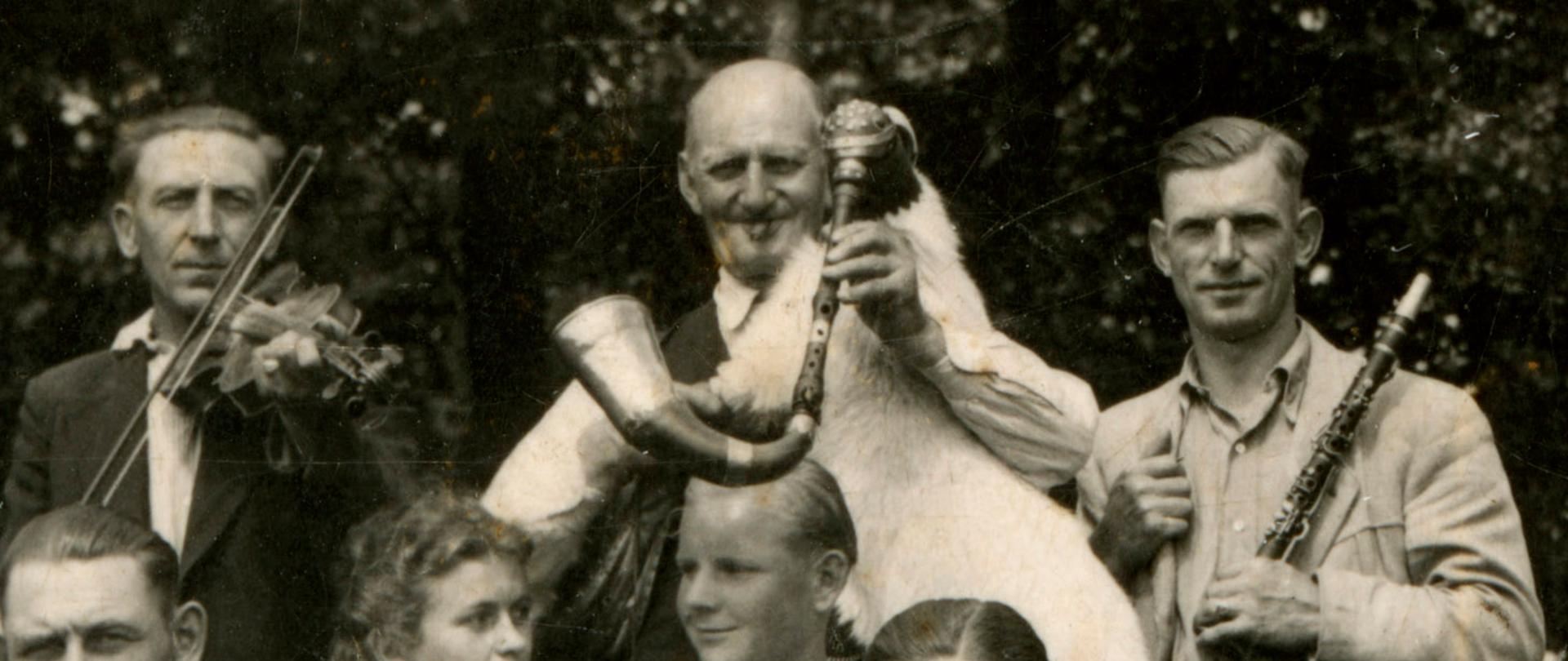 Zdjęcie przedstawia trzech muzykantów ludowych: pierwszy z lewej gra na skrzypcach, w środku na koźle weselnym, po prawej na klarnecie Es.