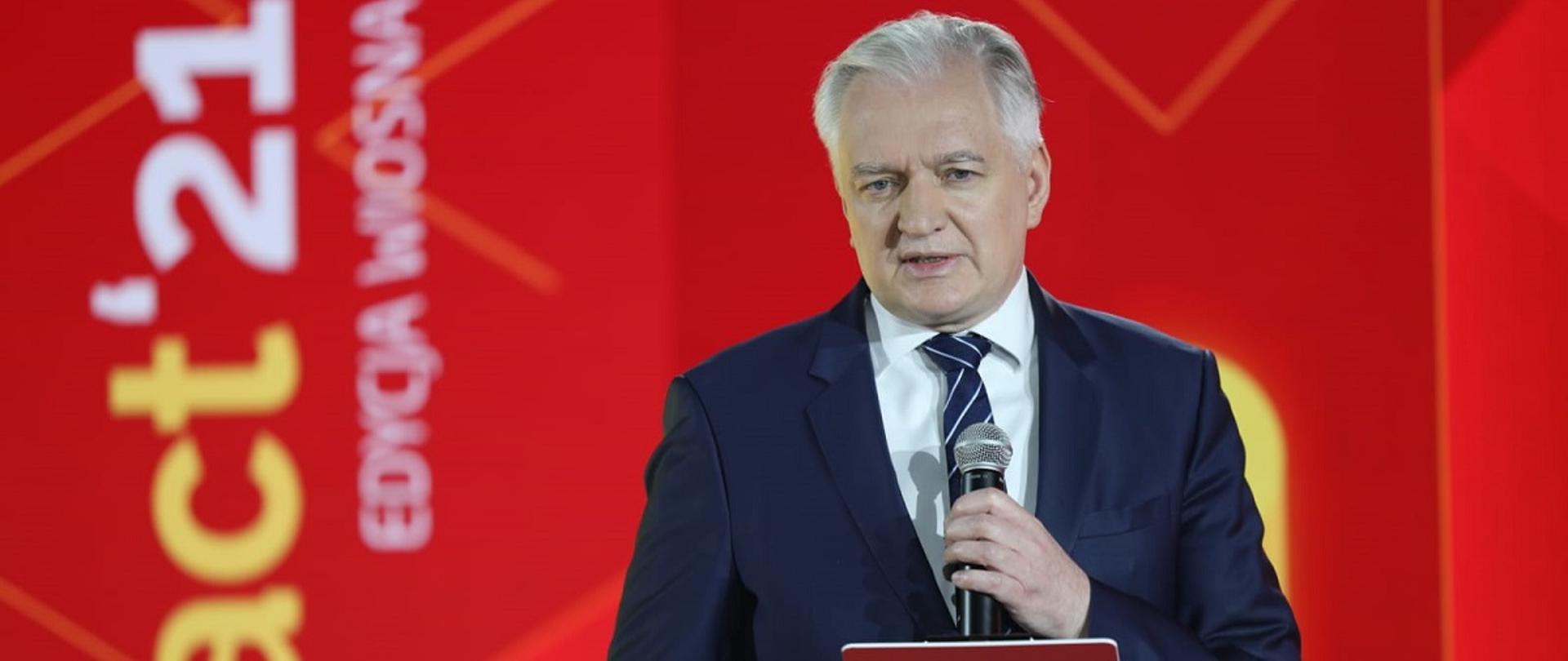 Wicepremier i minister rozwoju, pracy i technologii Jarosław Gowin podczas otwarcia wiosennej edycji Impact"21, z tyłu za jego placami logo Impact'21 na czerwonym tle