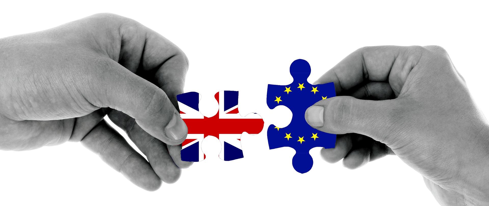 Dłonie z puzzlami w kolorach flag UE i Wielkiej Brytanii