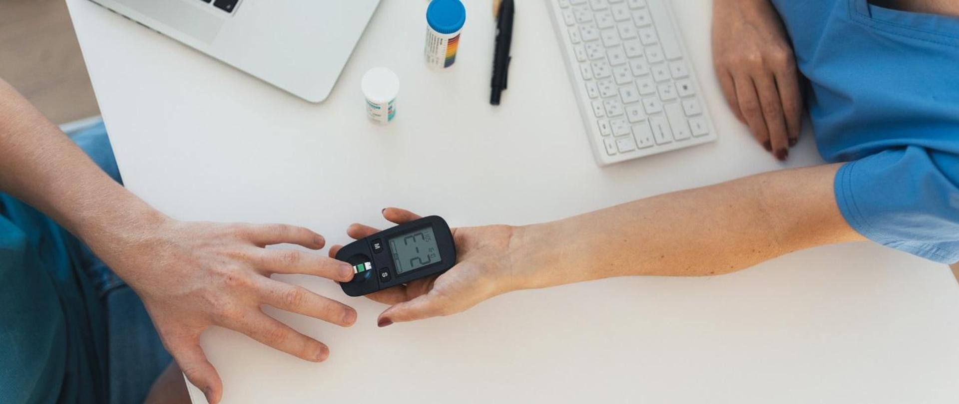 Zdjęcie z góry, widać rękę człowieka trzymającą małe urządzenie.