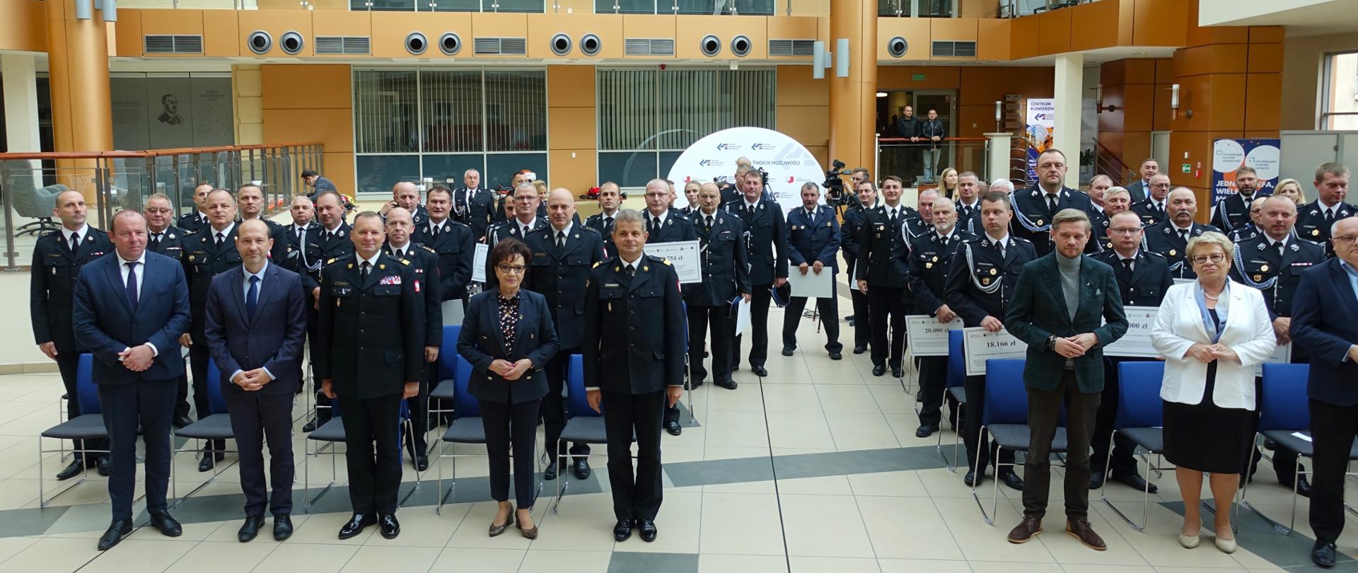 Kilkadziesiąt stojących osób w sali konferencyjnej Legnickiej Specjalnej Strefy Ekonomicznej podczas uroczystości