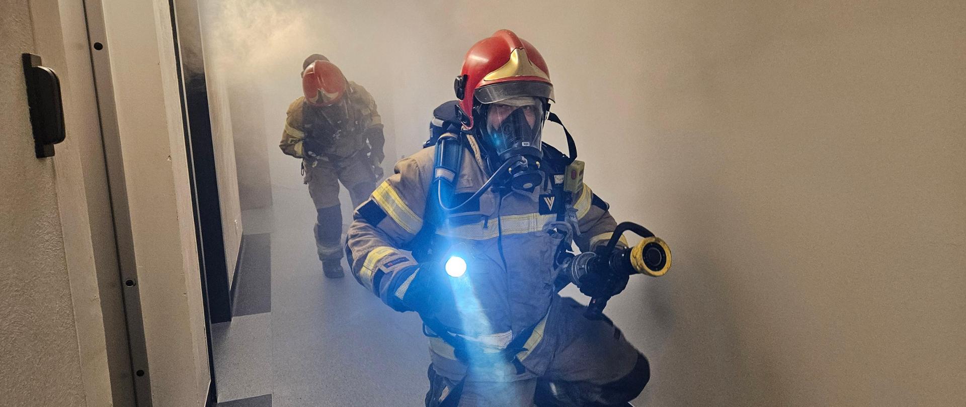 Rota strażaków poruszająca się po zadymionym korytarzu