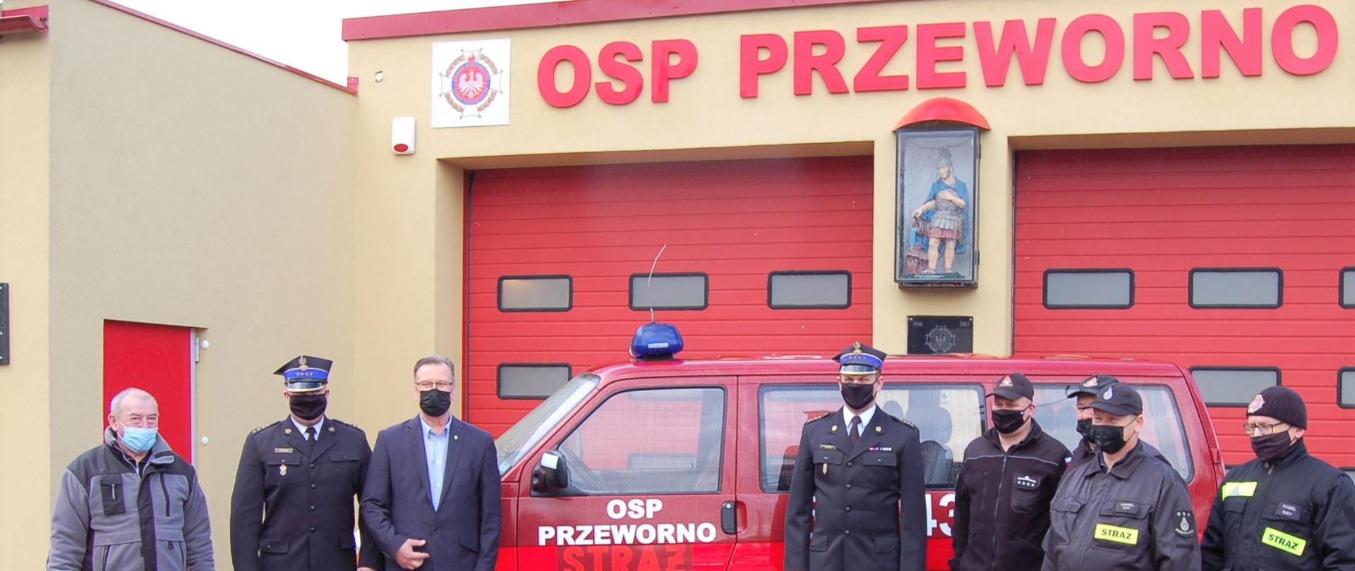 Strażacy stojący na tle remizy OSP w Przewornie i mikrobusa
