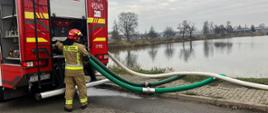 Na zdjęciu widoczny jest strażak obsługujący autopompę w trakcie realizacji ćwiczeń z przetłaczania i przepompowywania wody na duże odległości.