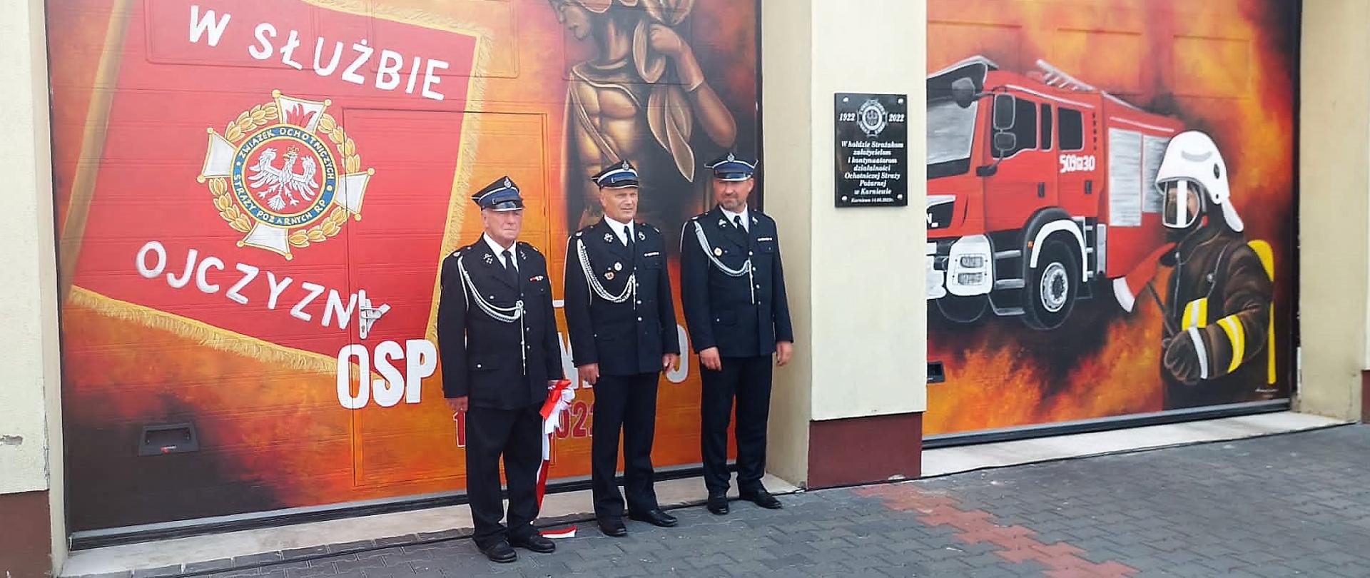 Druhowie OSP przy muralu na drzwiach garażowych 