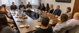 Szesnaście osób — funkcjonariuszy PSP i pracowników cywilnych — siedzi przy O‑kształtnym stole podczas oficjalnego spotkania w Komendzie Wojewódzkiej PSP w Opolu.