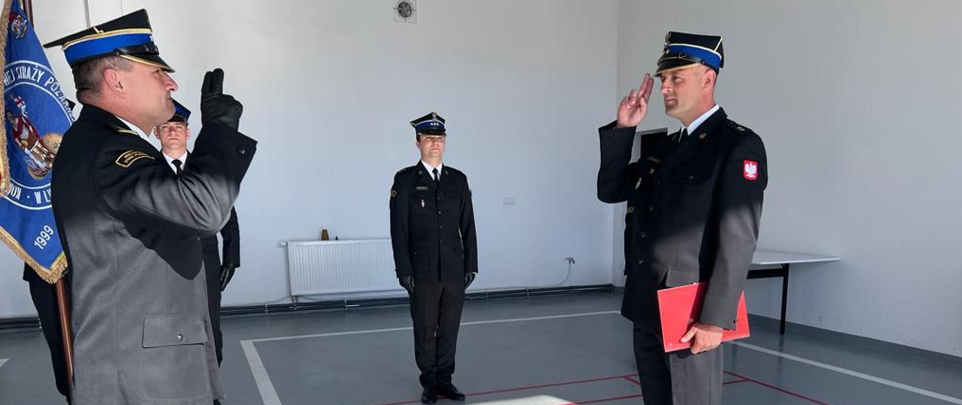 Zdjęcie przedstawia mianowanego na stanowisko dowódcy JRG mł. kpt. Grzegorza Falińskiego oraz Komendanta Powiatowego PSP w Lwówku Śląskim podczas mianowania. W tle widoczny jest zastępca dowódcy JRG kpt. Bartosz Lisowski. 