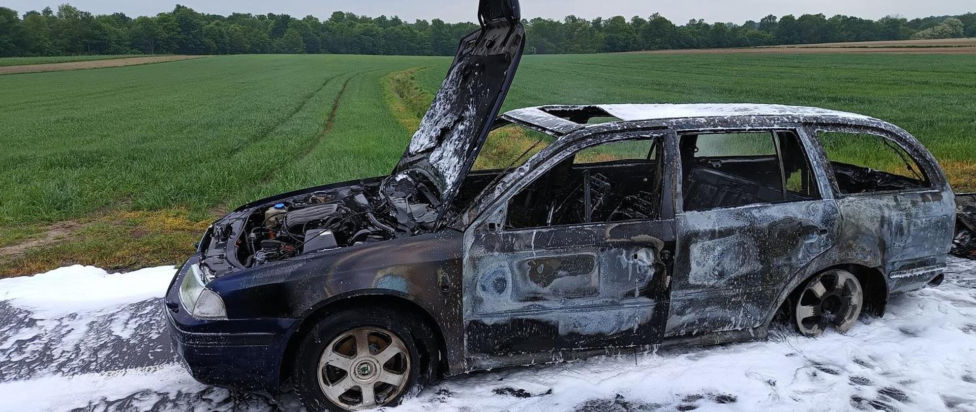 Spalony samochód osobowy polany pianą gaśniczą.