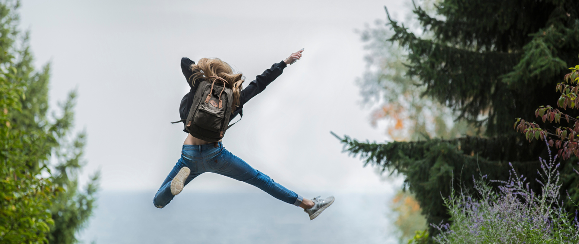 dziewczyna skacząca z plecakiem w lesie