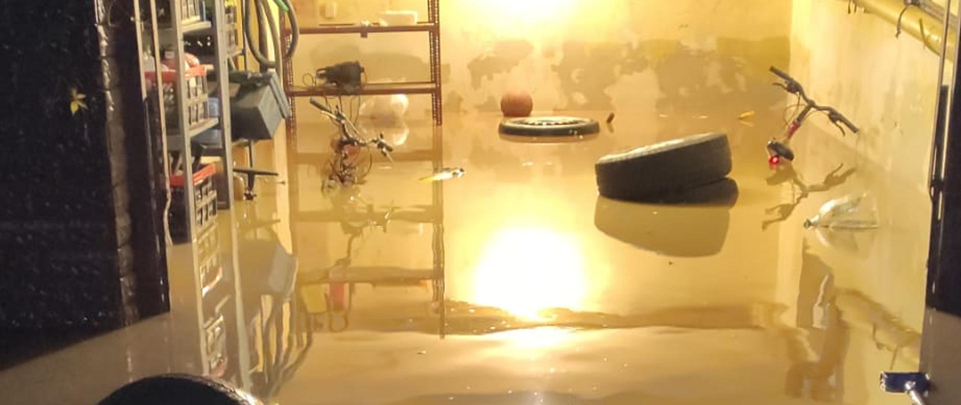 Na zdjęciu widoczne zalane pomieszczenia gospodarcze w budynku mieszkalnym. Częściowo widoczny wąż ssawny podłączony do pompy szlamowej.