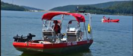 Widok z przodu. Centralnie jedna łódź pożarnicza, w tle druga podczas poszukiwań osoby zaginionej na tafli jeziora. 