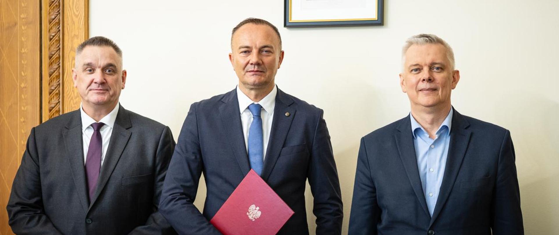 Na zdjęciu: po prawej minister Tomasz Siemoniak, w środku Cezary Luba, po lewej szef CBA Tomasz Strzelczyk. U góry zdjęcia widać fragment ramy, a po lewej stronie zdjęcia fragment drewnianych drzwi. 