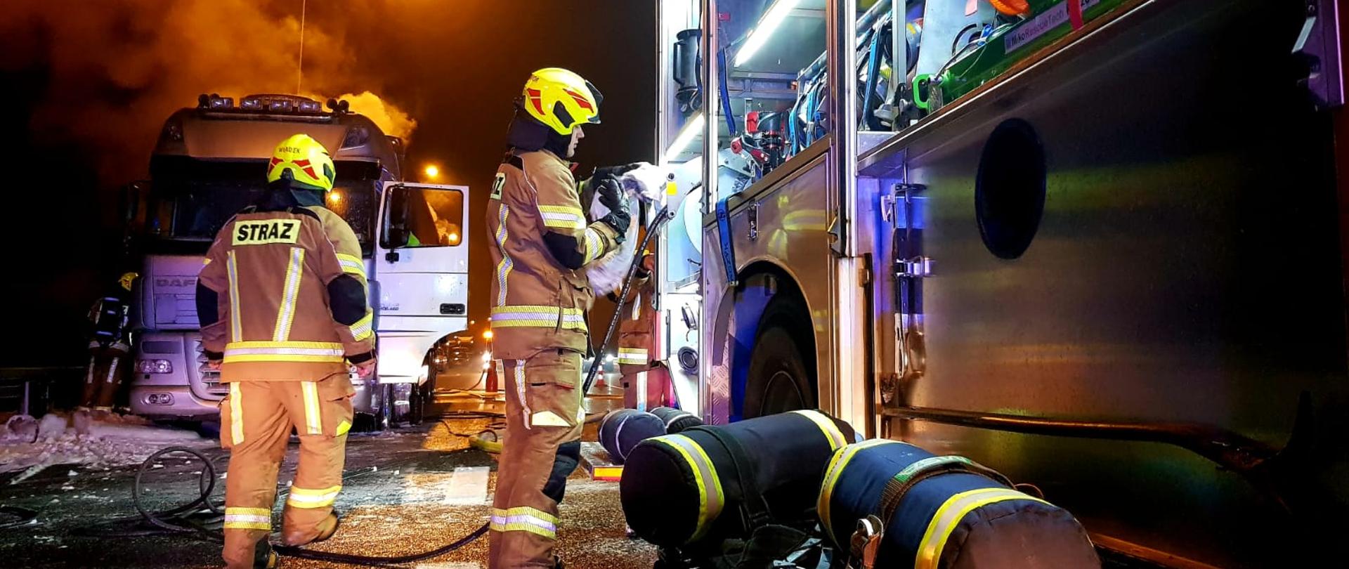 Na zdjęciu widzimy strażaków oraz palący się w tle ciągnik siodłowy