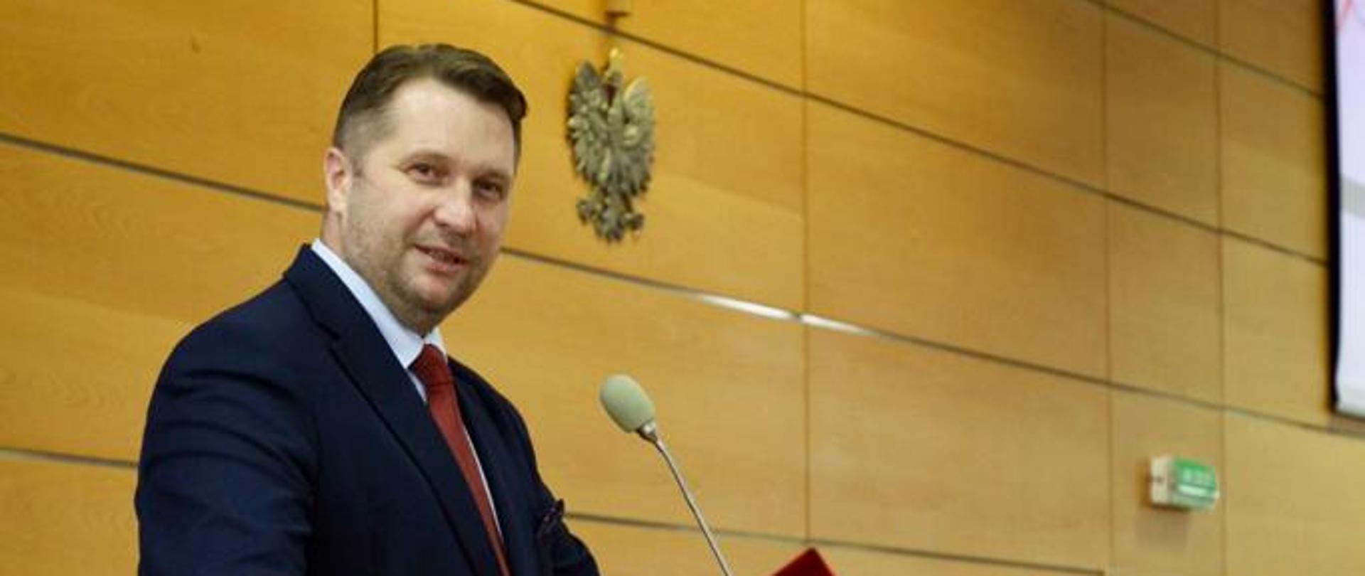 minister Czarnek przemawia do mikrofonu podczas inauguracji w Toruniu. z prawej strony siedzą przedstawiciele władz uczelni