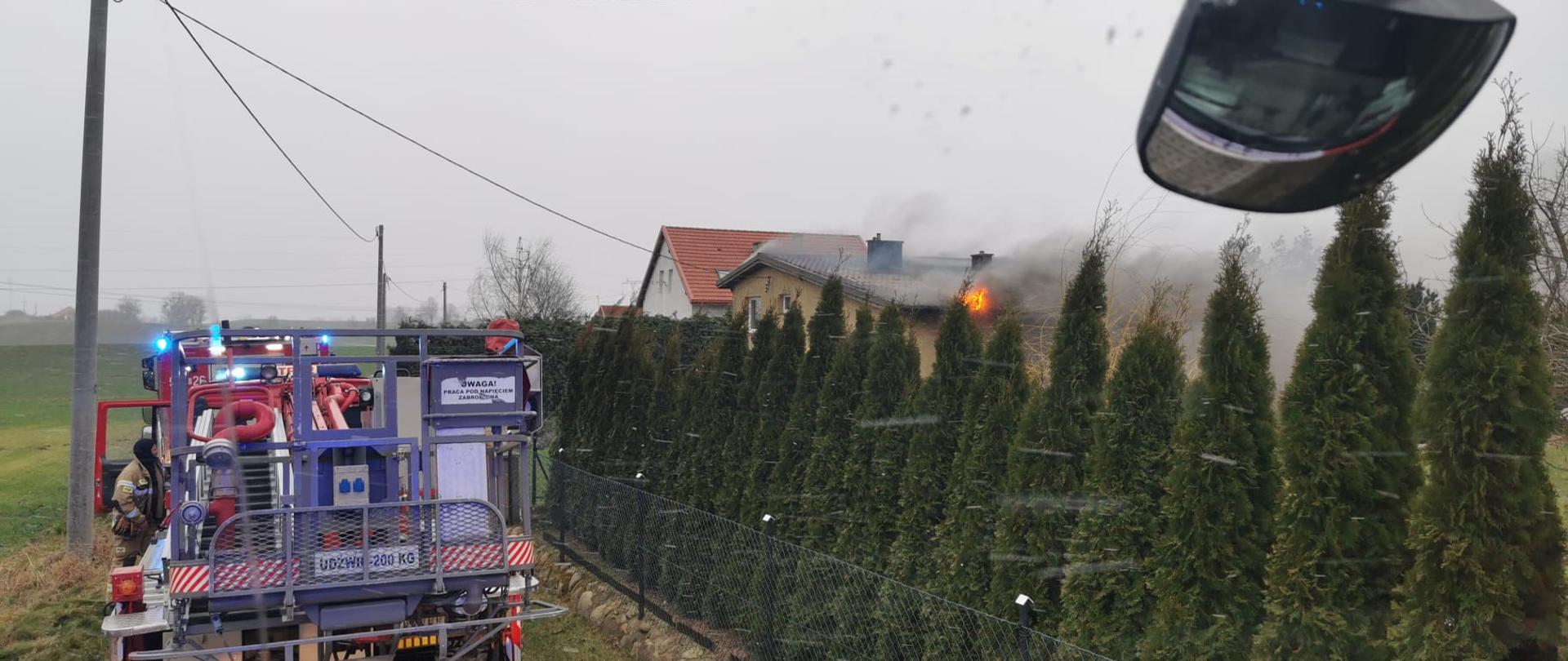 pora dzienna. Na zdjęciu widać z lewej strony podnośnik mechaniczny JRG Sztum, po lewej stronie za ogrodzeniem z drzewek dom z płonącym poszyciem dachu