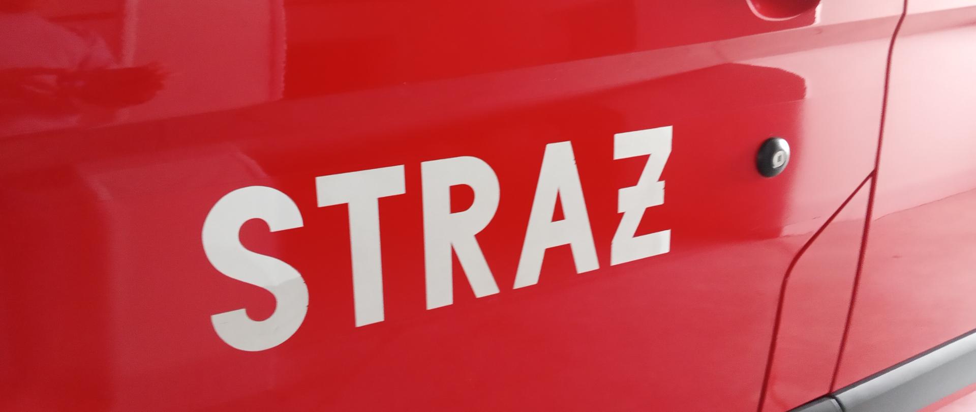 zdjęcie przedstawia napis na drzwiach samochodowych STRAŻ 
