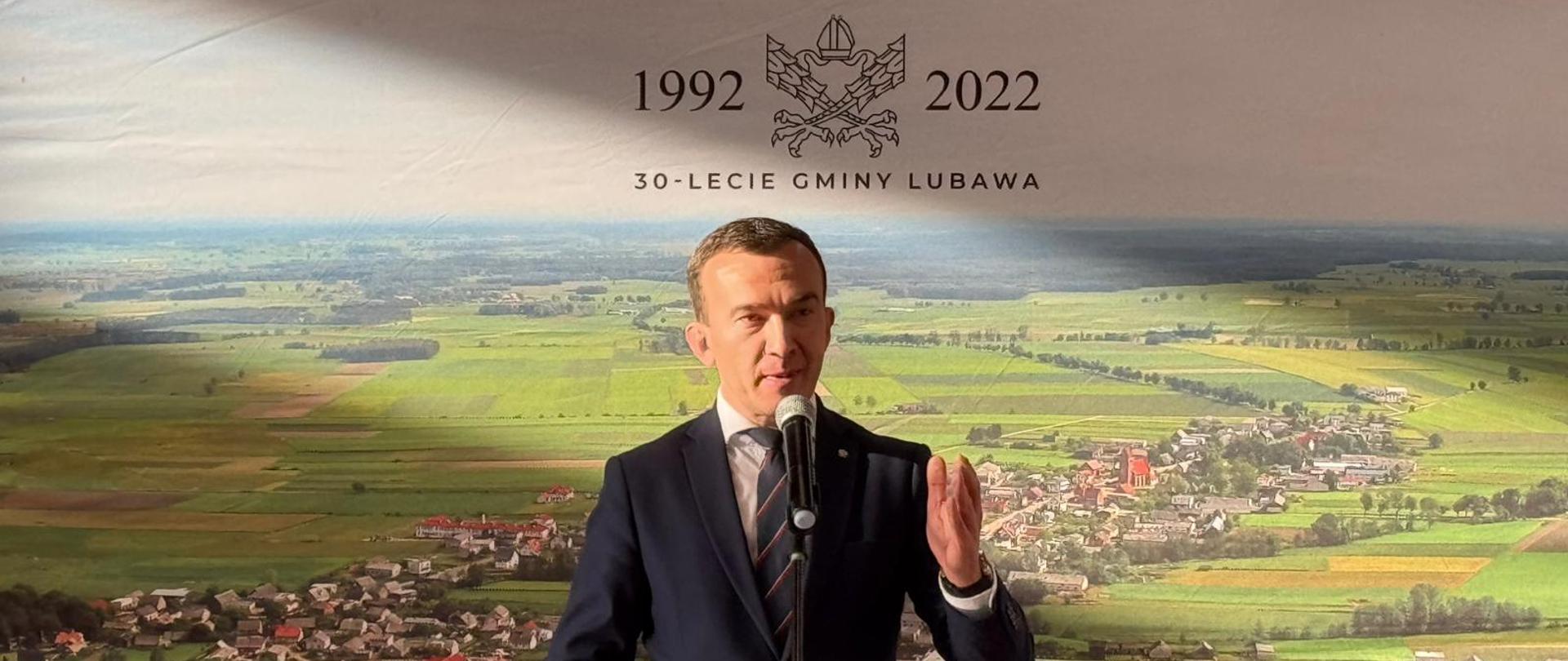 Mężczyzna stoi w garniturze i przemawia