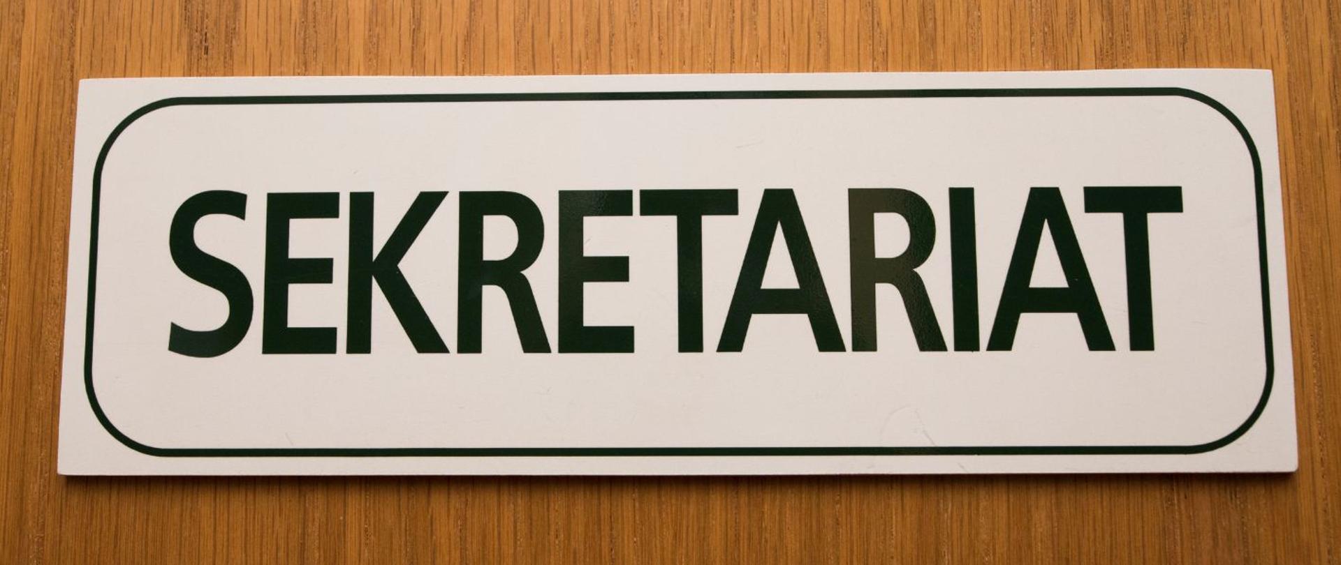 Białe tło, zdjęcie napisu sekretariat na drewnianym tle.