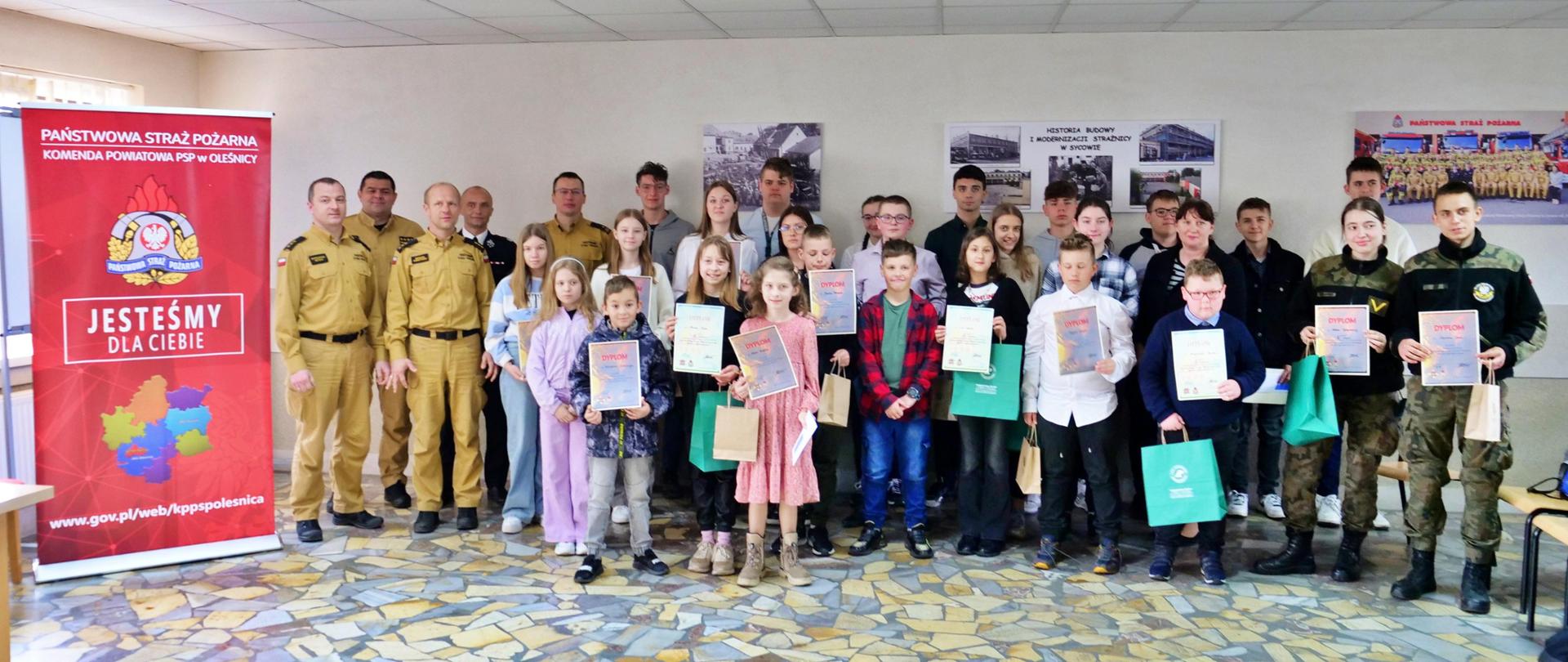 Na zdjęciu znajdują się uczestnicy eliminacji powiatowych Ogólnopolskiego Turnieju Wiedzy Pożarniczej wraz z komisją sędzią egzaminacyjną oraz p.o. Komendantem Powiatowym