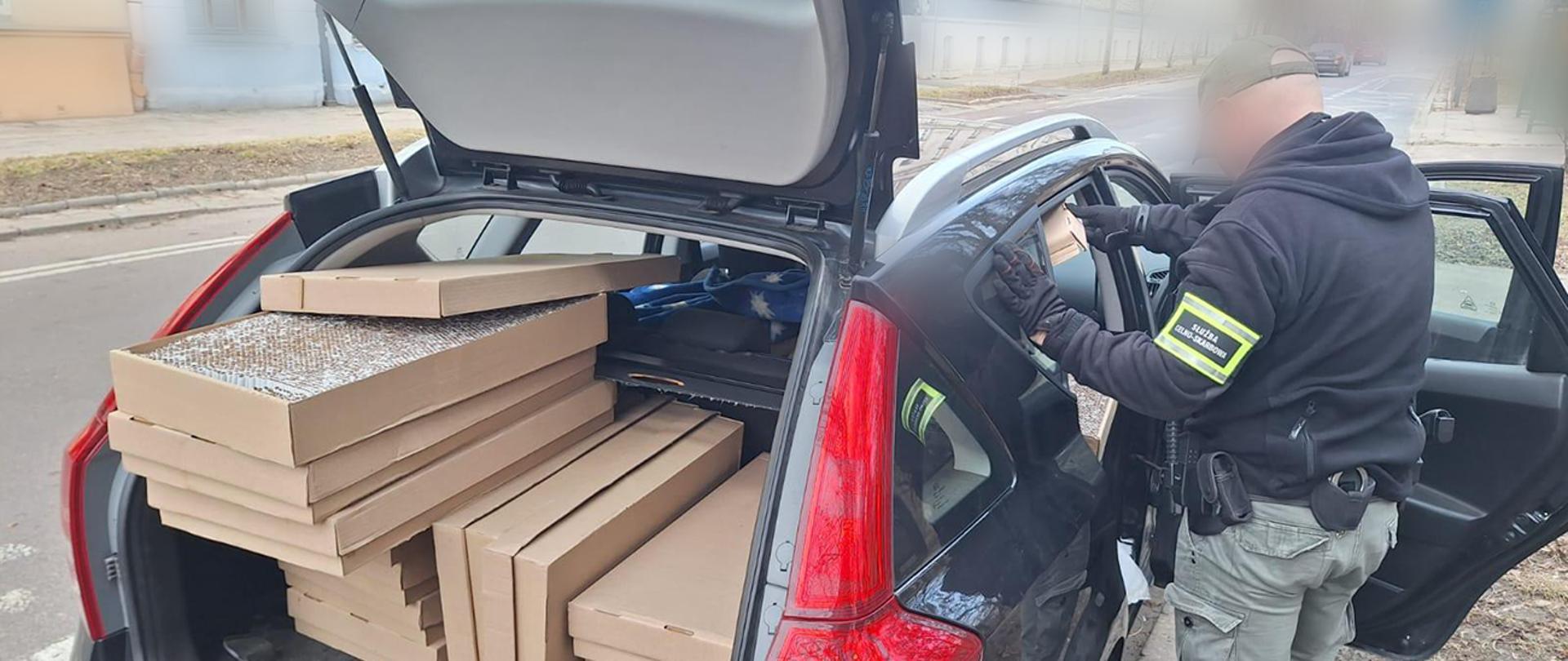 Nielegalne papierosy w samochodzie, oglądane przez funkcjonariusza. 