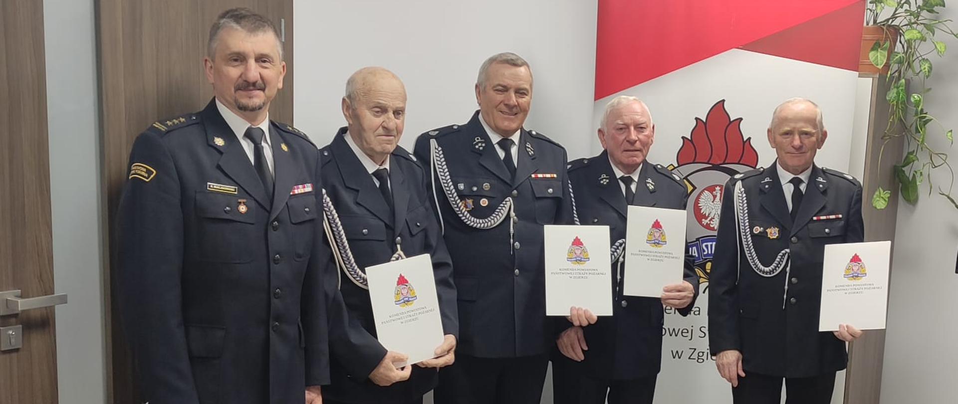 Zdjęcie przedstawia Komendanta Powiatowego PSP w Zgierzu oraz druhów, którzy otrzymali decyzję o przyznaniu świadczenia.
