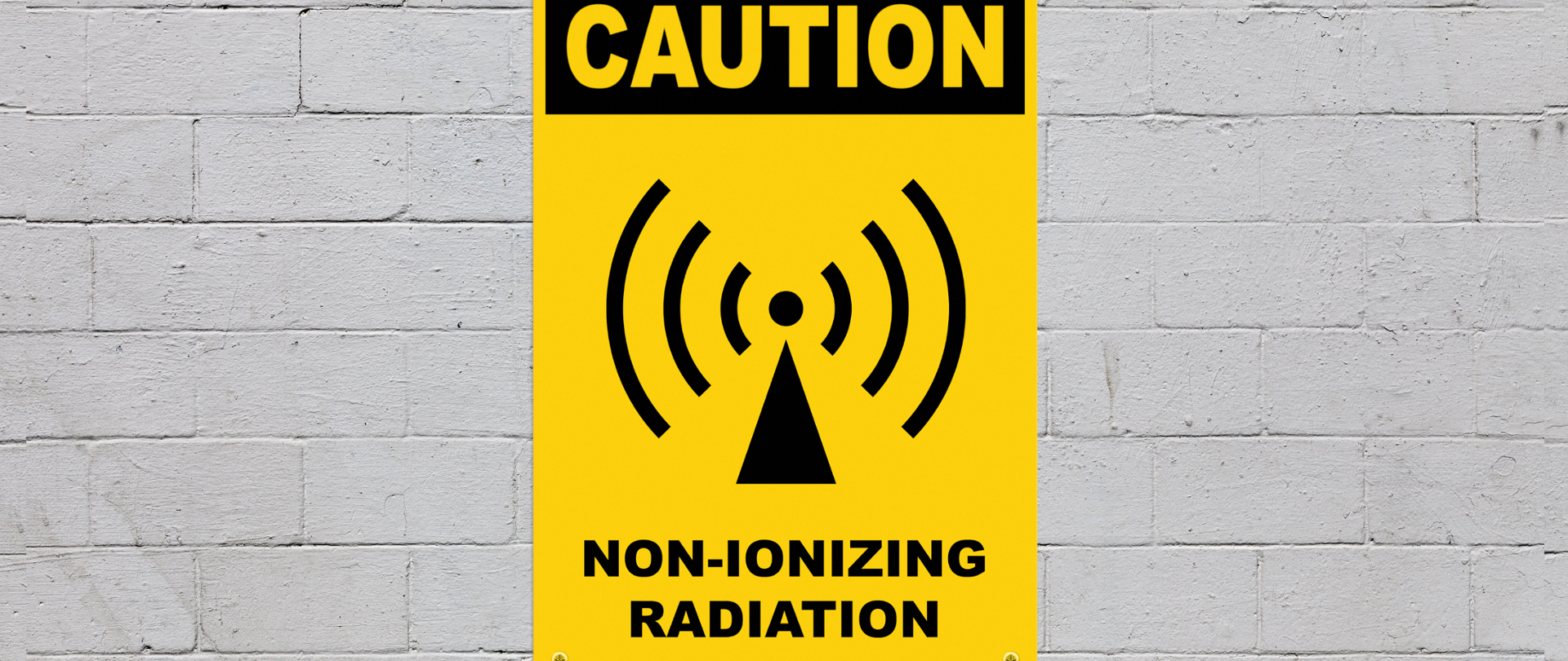 Mur z tablicą informacyjną z napisem "Caution, non-ionizing radiation"