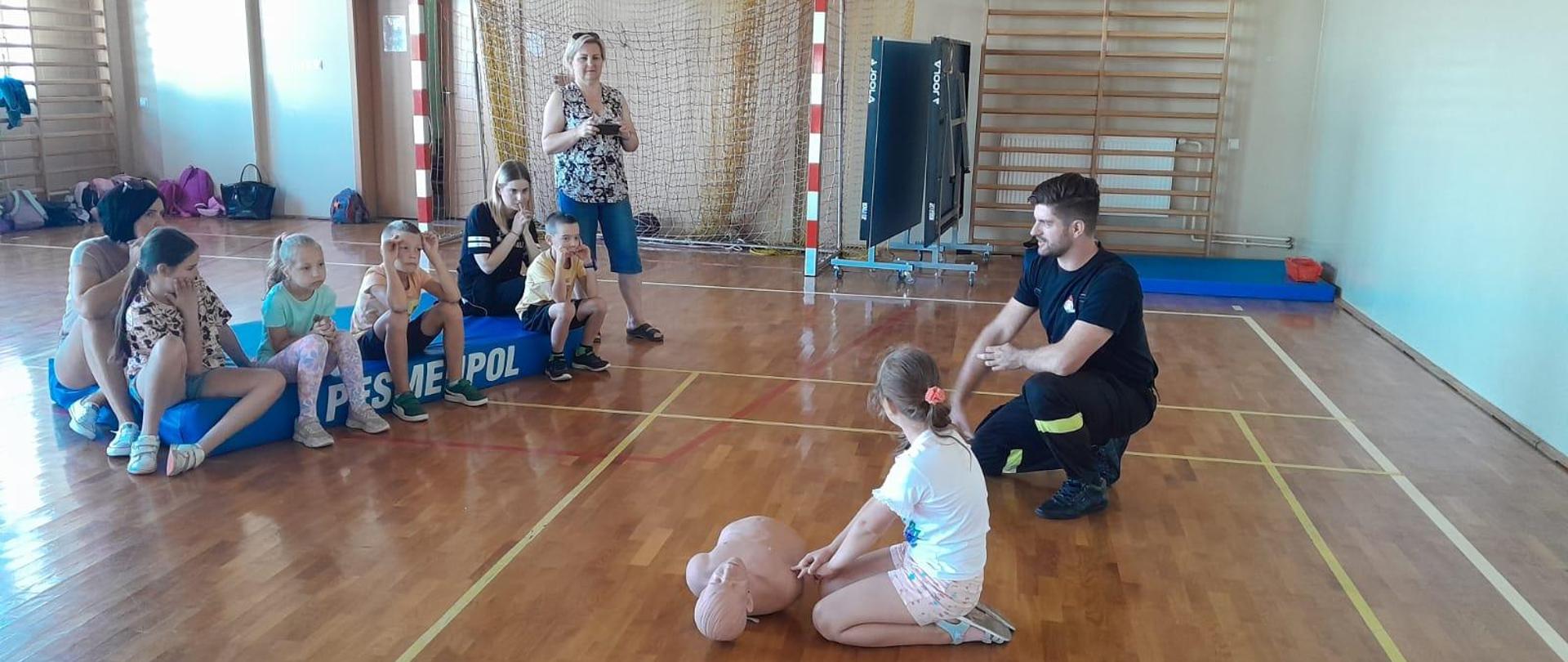 Zdjęcie przedstawia strażaka udzielającego szkolenia z zakresu KPP dla dzieci.