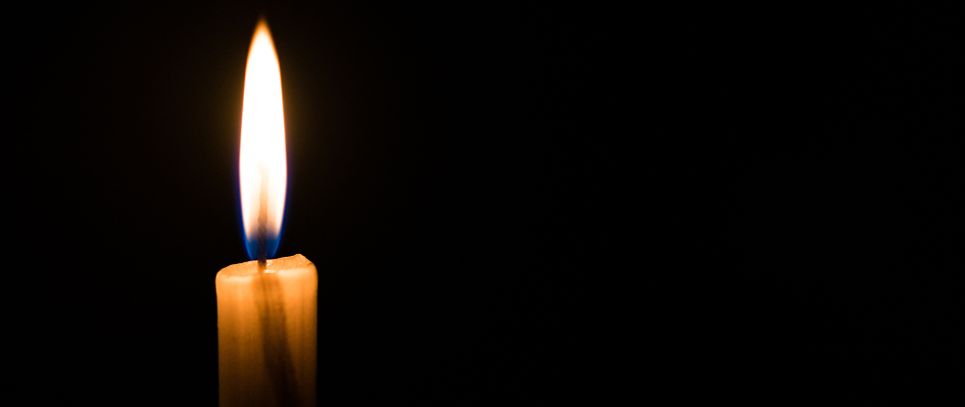 paląca się świeczka na czarnym tle 