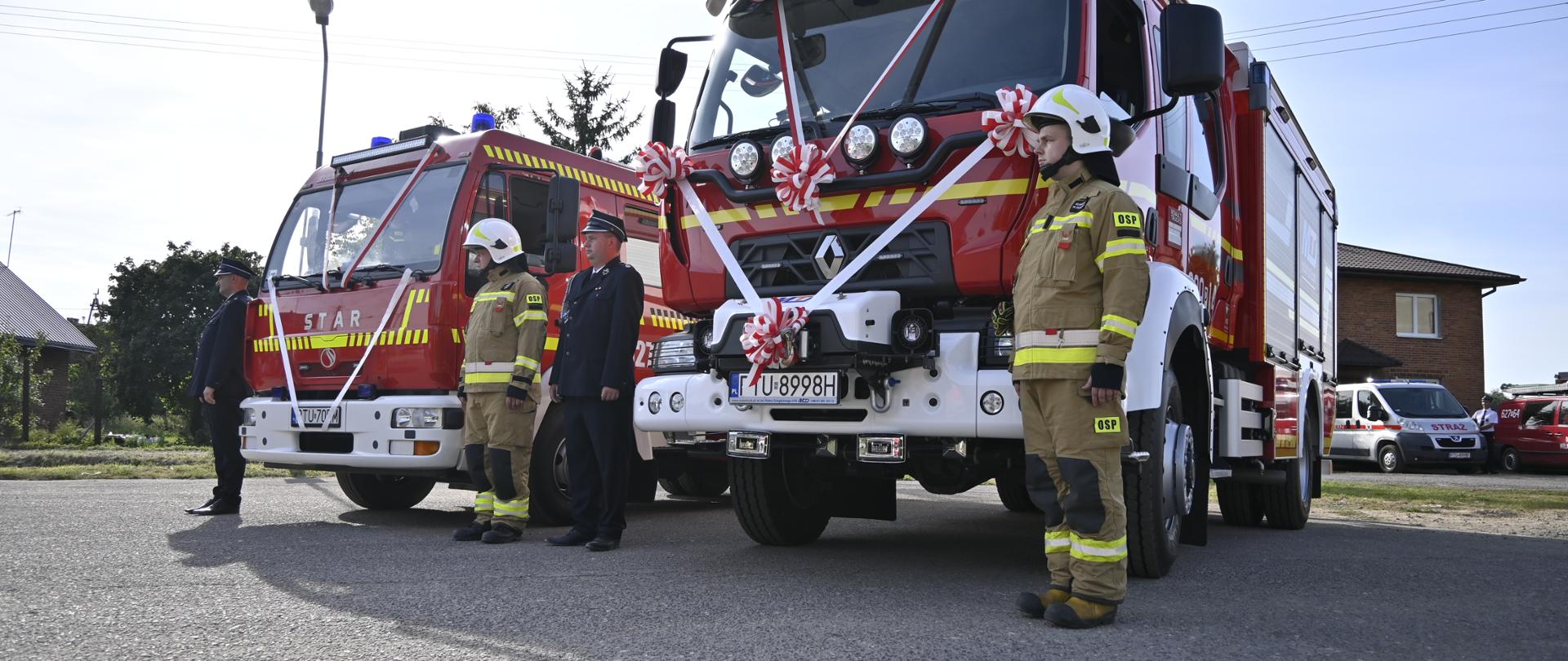 Strażacy przy nowych przekazanych pojazdach pożarniczych.
