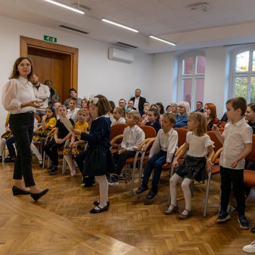 Pasowanie na ucznia. Uczniowie i publiczność zgromadzona na uroczystości podczas rozwiązywania zagadki przygotowanej przez nauczycielki.