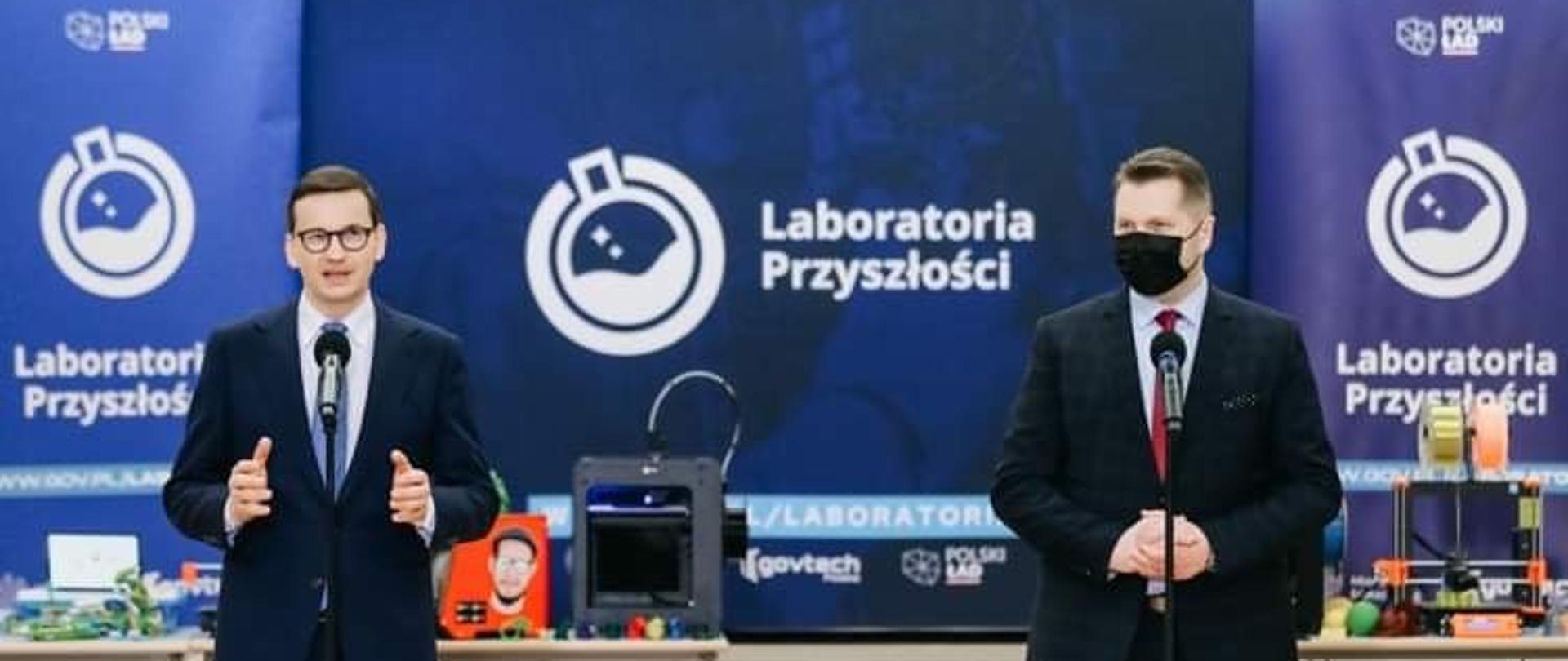Na zdjęciu po lewej przemawiający Premier Mateusz Morawiecki, obok niego Minister Edukacji i Nauki Przemysław Czarnek. W tle ścianka Laboratoria Przyszłości i sprzęt, który można zakupić w ramach programu. 