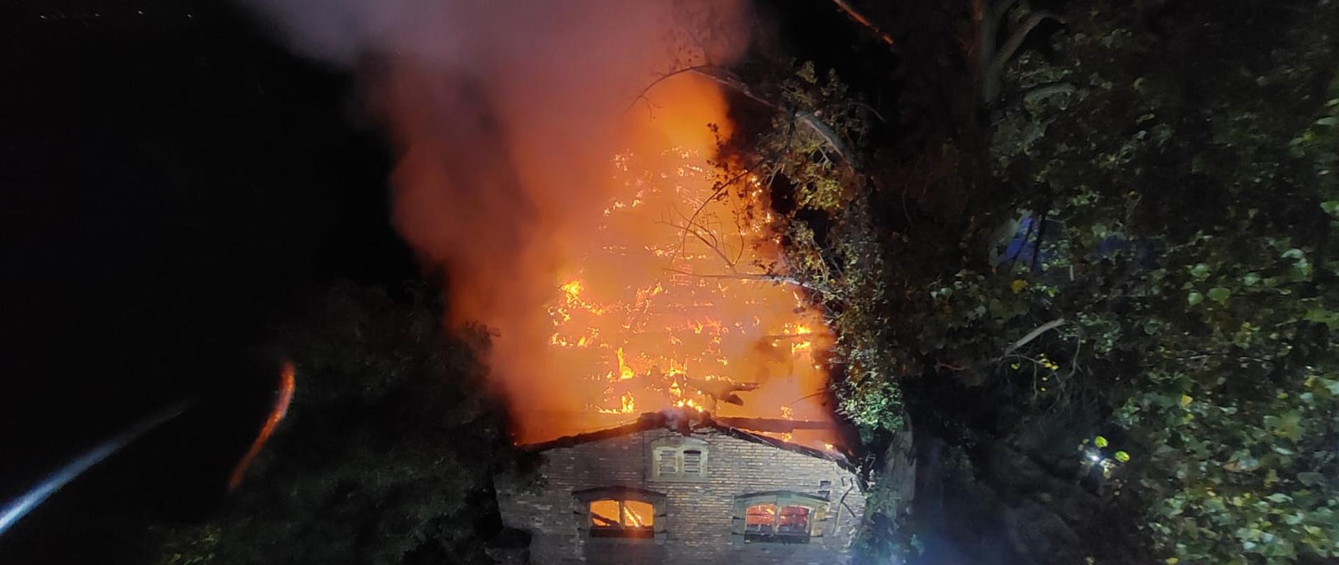 Zdjęcie przedstawia palący się opuszczony budynek - fotografia zrobiona z wysokości przy użyciu pojazdu specjalnego typu drabina.