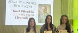 Uczniowie prezentują dyplomy na tle ekranu z napisem Szkolny Konkurs Historyczny „Józef Piłsudski - człowiek czynu i legendy” 