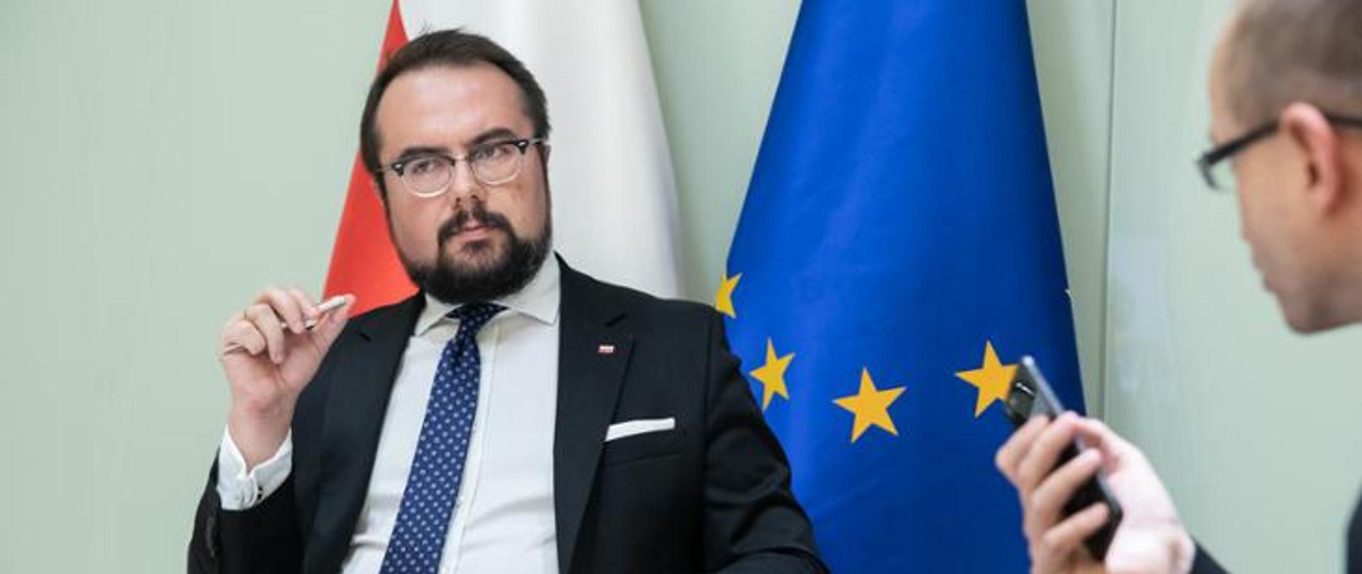 mężczyzna w garniturze na tle flag